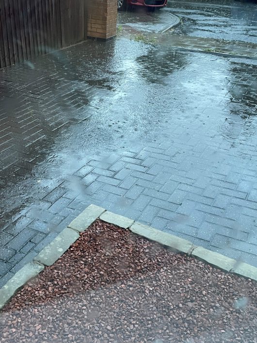 Sloping driveway photograph shows the pavers filled flush to the surface only. This newly constructed build-up accepts the rainfall rather than running off onto the pavement and highway.